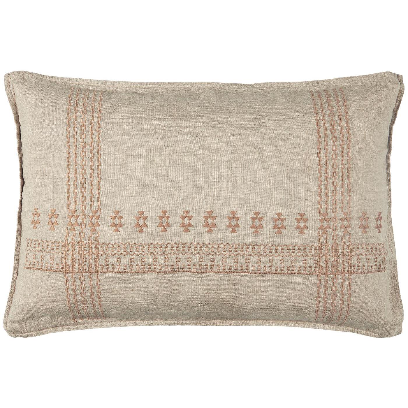 Un coussin rectangulaire en tissu beige clair avec des broderies géométriques dans des tons de terre cuite. Les motifs, inspirés d’un style artisanal, se répètent horizontalement au centre et verticalement aux extrémités, donnant un aspect délicatement travaillé au coussin.