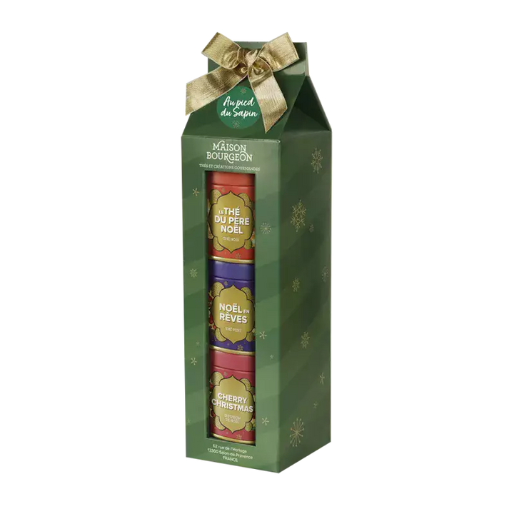 Coffret cadeau "Au pied du Sapin" de la Maison Bourgeon, orné d'un ruban doré. Ce coffret festif contient trois boîtes de thés et infusions de Noël : "Le Thé du Père Noël", "Noël en Rêves" et "Cherry Christmas". Présenté dans un emballage vert décoré de flocons de neige, ce coffret est idéal pour célébrer les fêtes avec des saveurs chaleureuses et gourmandes.