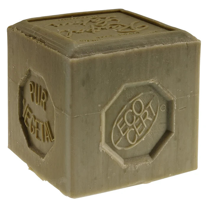 Un savon en cube de la marque Rampal Latour, étiqueté 'Pur Végétal' et portant le label 'ECOCERT'. Le savon est de couleur vert olive avec une texture légèrement rugueuse. Il présente des inscriptions en relief qui indiquent qu'il est fait à partir d'ingrédients d'origine végétale. Le savon est placé sur une surface neutre, soulignant son aspect naturel et écologique.