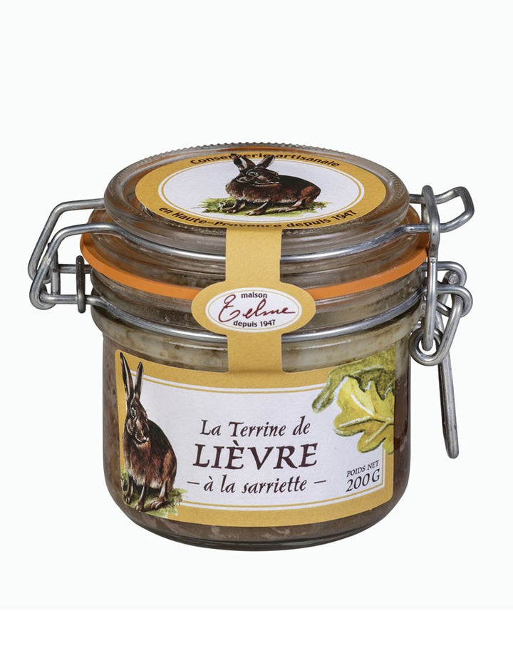 Terrine de Lièvre à la Sarriette de la Maison Telme, présentée dans un pot en verre avec une étiquette jaune. L'étiquette montre une illustration de lièvre et des feuilles de sarriette, soulignant le caractère naturel et artisanal de cette spécialité de Haute-Provence.